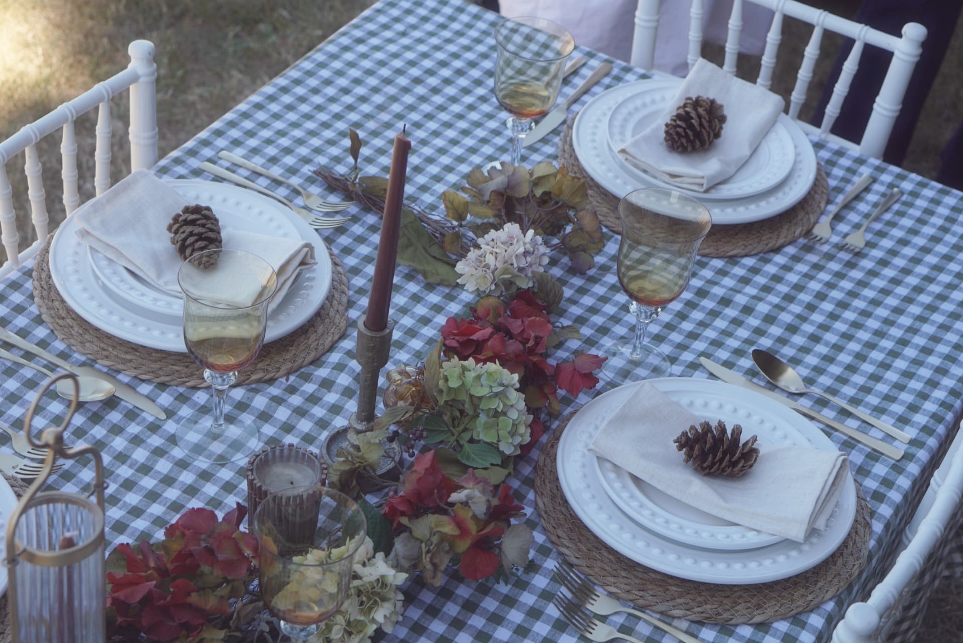 Overhead view of the fall harvest tablescape with a foliage runner down the center of a green gingham table